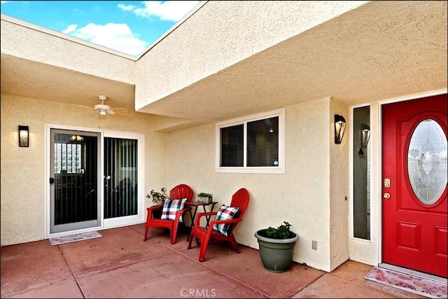 doorway to property with a ceiling fan and stucco siding