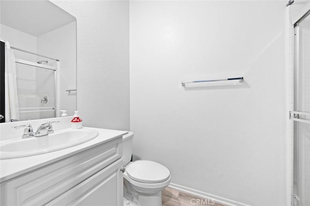 bathroom featuring vanity, a shower with shower door, and toilet