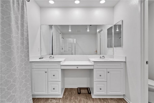 bathroom with hardwood / wood-style floors, toilet, vanity, and an enclosed shower