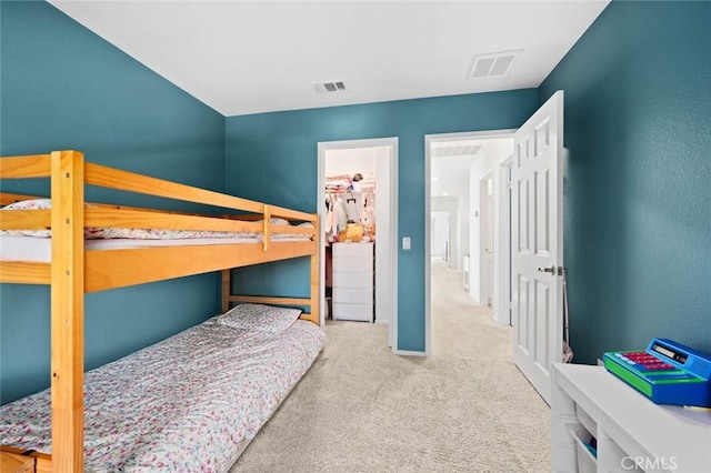 bedroom with a spacious closet, a closet, and light carpet