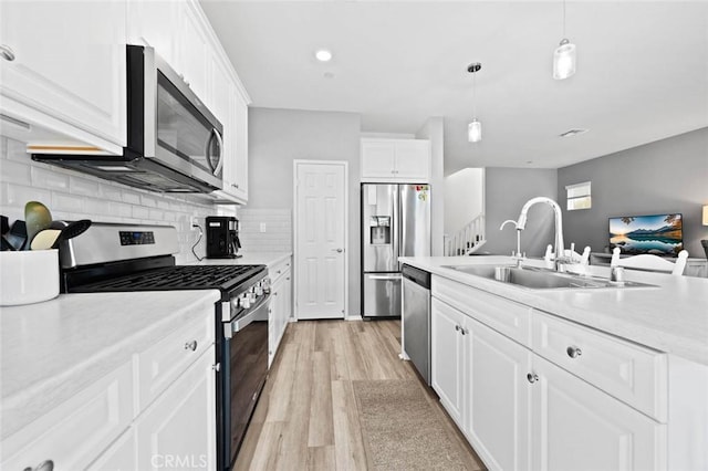 kitchen with sink, pendant lighting, white cabinets, and stainless steel appliances