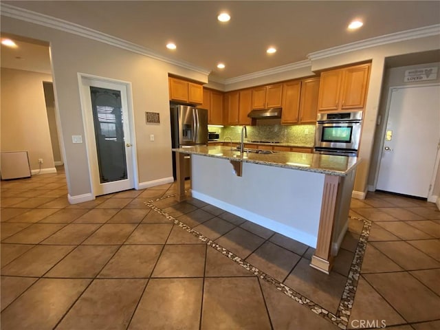 kitchen with tile patterned flooring, stainless steel appliances, backsplash, a kitchen island with sink, and a breakfast bar area