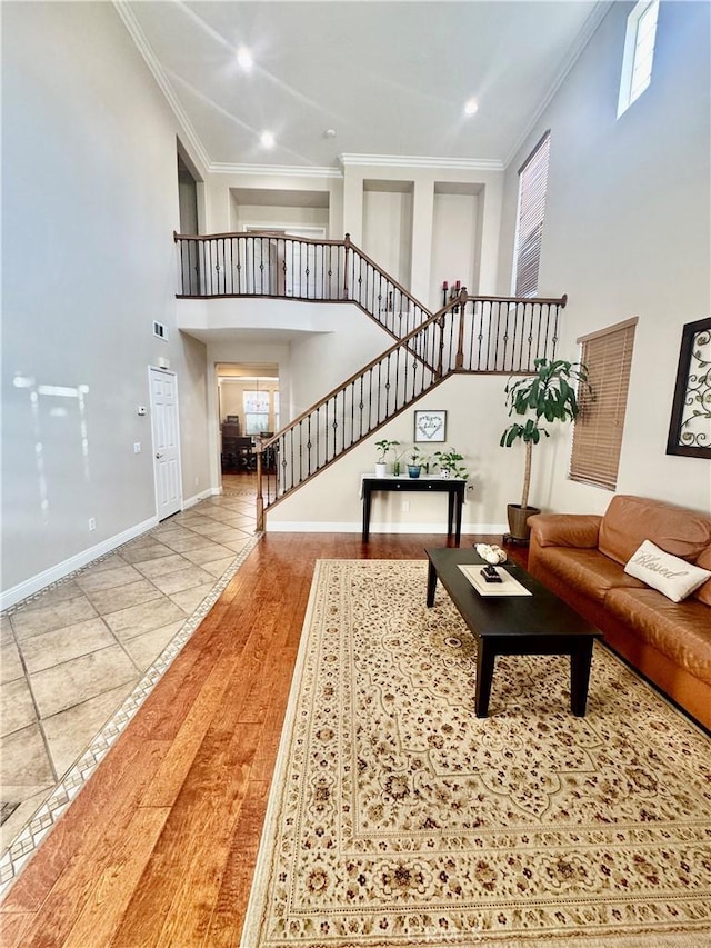 living room featuring a towering ceiling, crown molding, and hardwood / wood-style floors