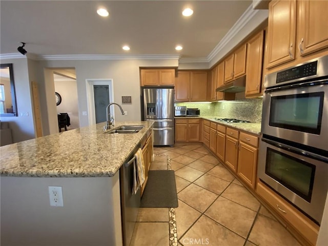 kitchen with appliances with stainless steel finishes, sink, light tile patterned flooring, ornamental molding, and a center island with sink