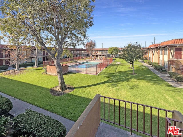 view of home's community with a pool and a yard