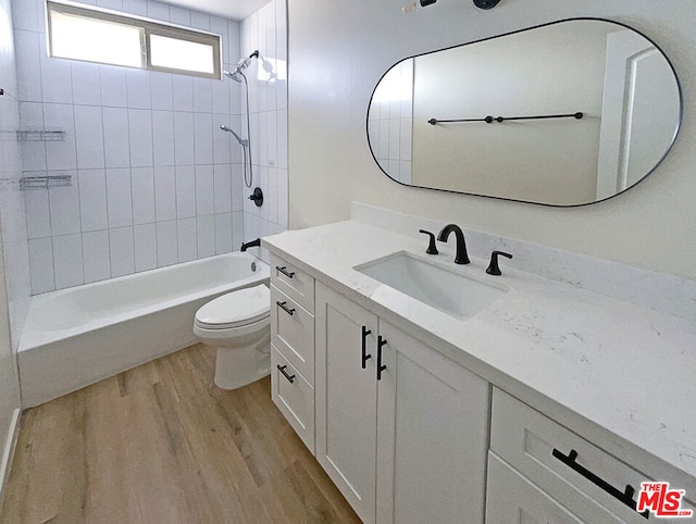 full bathroom featuring vanity, toilet, tiled shower / bath combo, and wood-type flooring