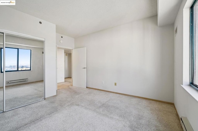 unfurnished bedroom featuring a closet, a baseboard radiator, and light carpet