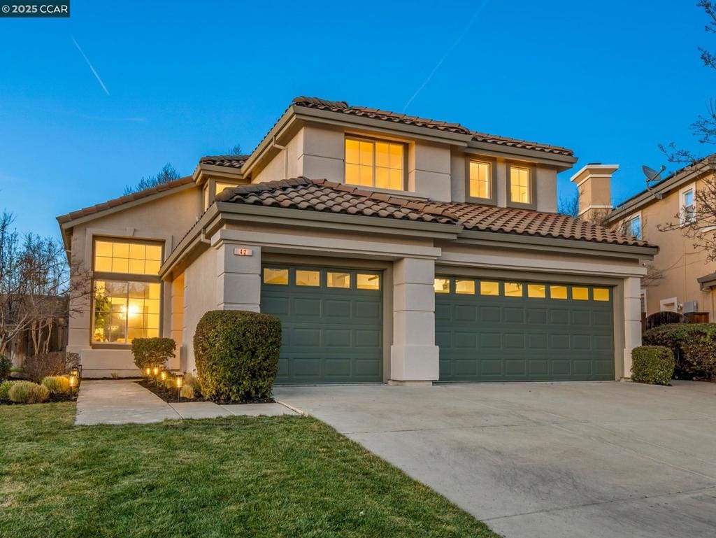 mediterranean / spanish-style house featuring a garage and a front lawn