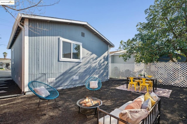 back of house with an outdoor living space with a fire pit