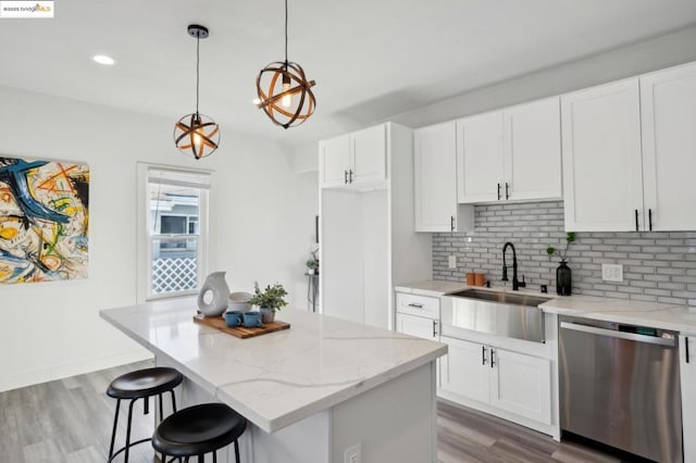 kitchen featuring white cabinetry, hanging light fixtures, stainless steel dishwasher, and sink