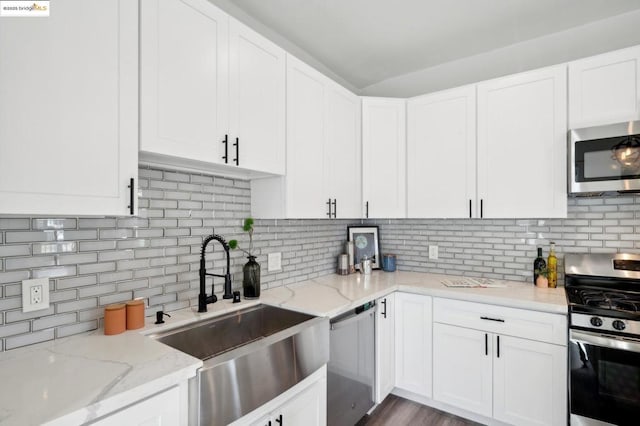 kitchen with white cabinets, appliances with stainless steel finishes, light stone countertops, and backsplash