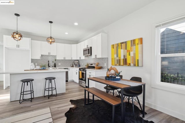 kitchen featuring stainless steel appliances, white cabinetry, a wealth of natural light, and pendant lighting