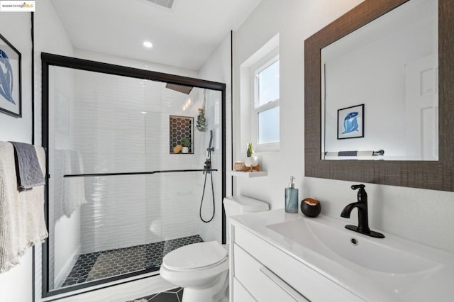 bathroom featuring a shower with door, vanity, and toilet