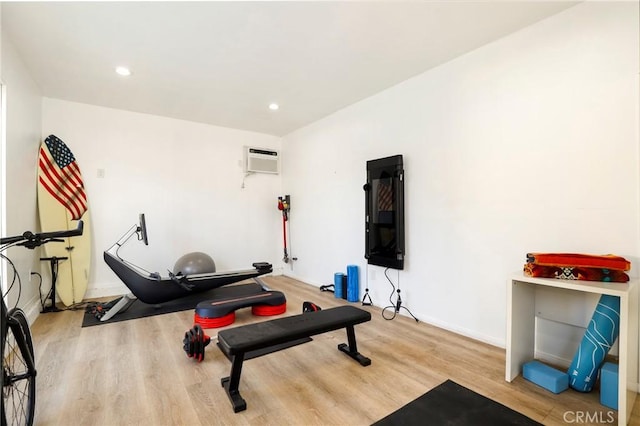 workout room featuring a wall mounted air conditioner and light hardwood / wood-style flooring