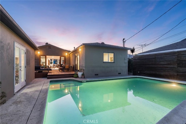 pool at dusk featuring french doors and a deck