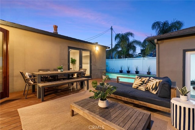 deck at dusk with a fenced in pool