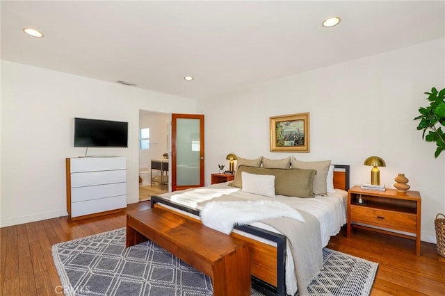 bedroom with hardwood / wood-style flooring and connected bathroom