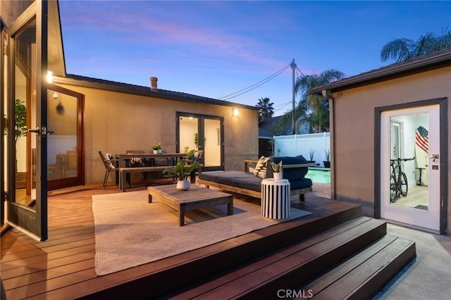 deck at dusk featuring a fenced in pool