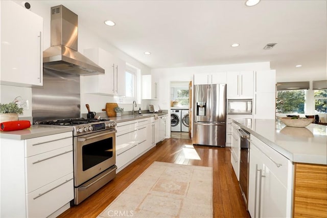 kitchen with white cabinetry, washing machine and clothes dryer, stainless steel appliances, and extractor fan