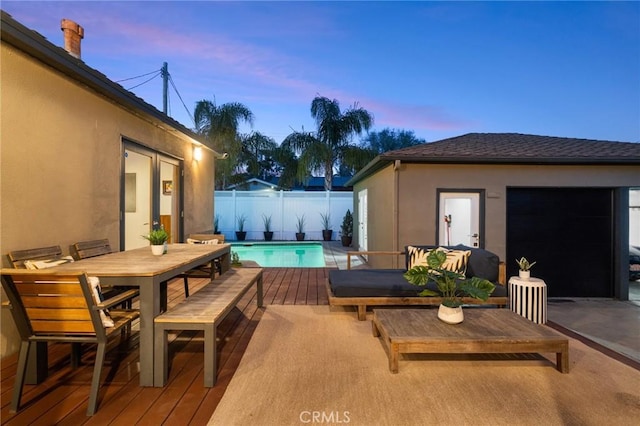 deck at dusk featuring a fenced in pool and a patio area