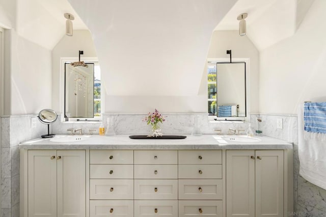 bathroom with tile walls, vaulted ceiling, and vanity