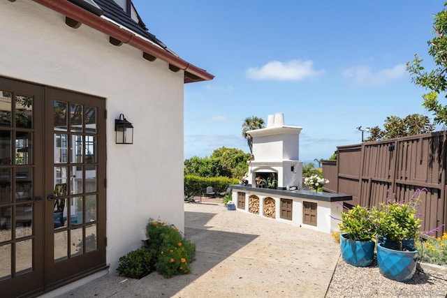 view of patio featuring exterior fireplace, an outdoor kitchen, and french doors