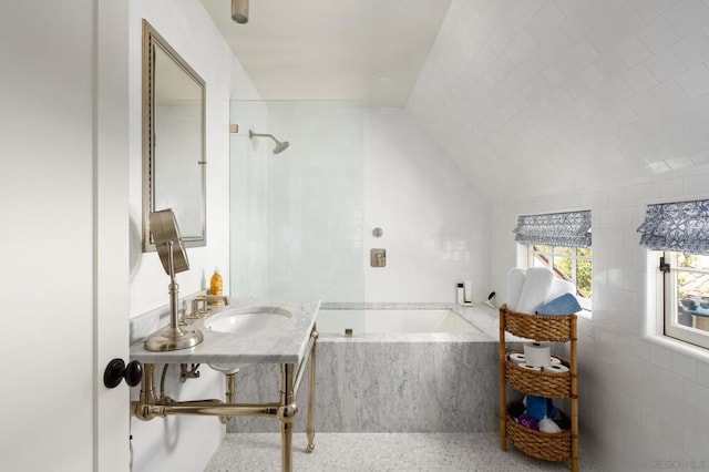 bathroom with sink, tile walls, separate shower and tub, and vaulted ceiling