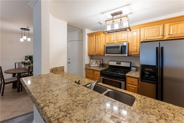 kitchen with light stone counters, kitchen peninsula, stainless steel appliances, and hanging light fixtures