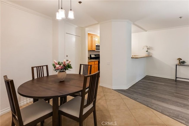 dining area featuring ornamental molding and light tile patterned flooring