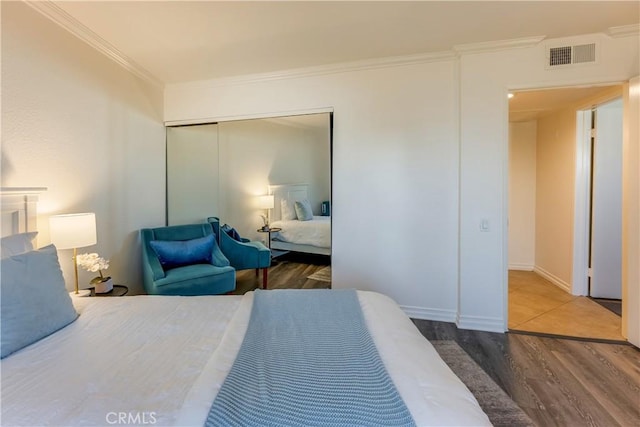 bedroom with a closet, hardwood / wood-style flooring, and ornamental molding