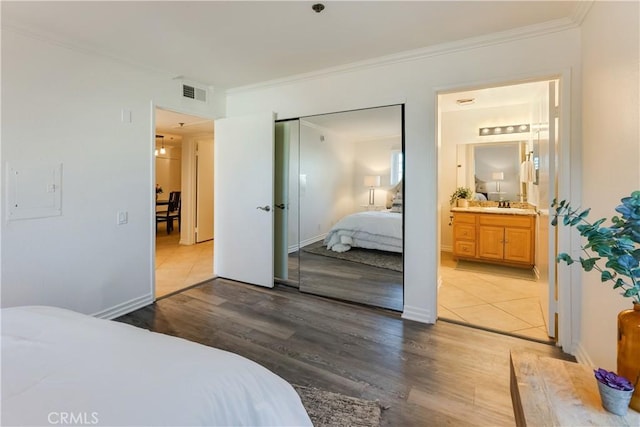 bedroom with sink, hardwood / wood-style floors, ensuite bath, and crown molding