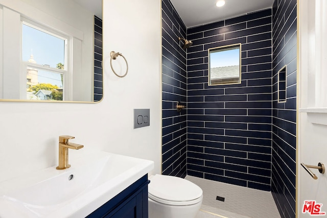 bathroom featuring a tile shower, toilet, and vanity