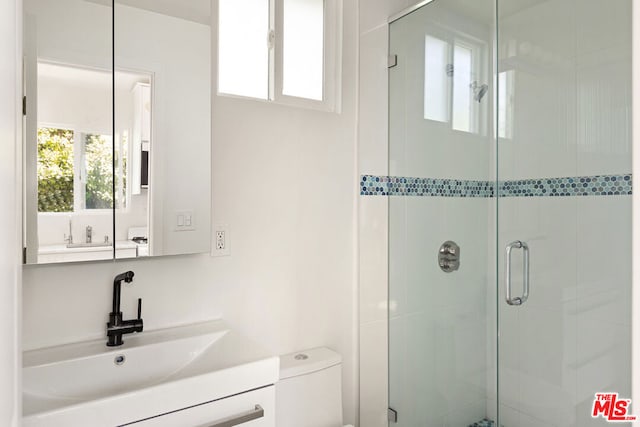 bathroom with vanity, toilet, and a shower with door