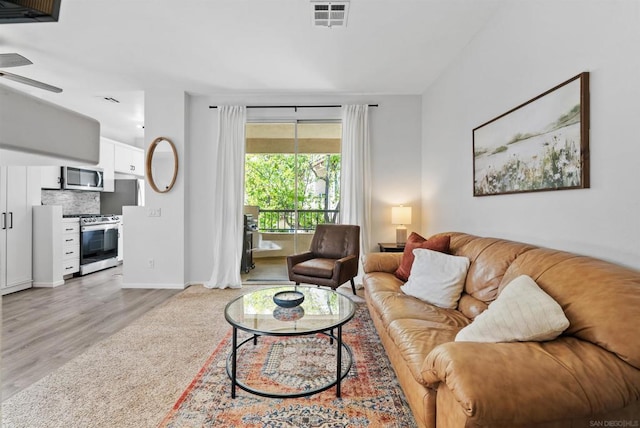 living room with light hardwood / wood-style floors and ceiling fan