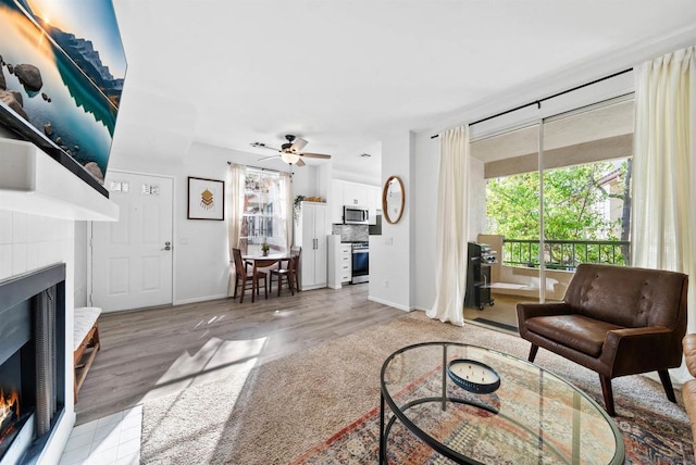 living room with ceiling fan, a fireplace, and light hardwood / wood-style flooring