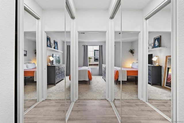 bedroom featuring multiple closets and light hardwood / wood-style flooring