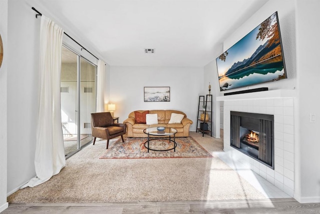 carpeted living room with a tiled fireplace