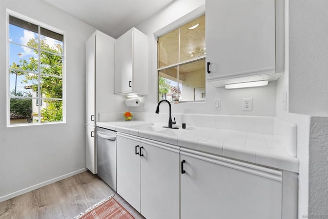 kitchen featuring white cabinetry, sink, tile counters, and light hardwood / wood-style flooring