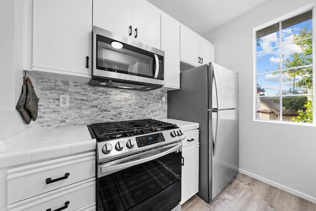 kitchen with white cabinetry, decorative backsplash, tile counters, and appliances with stainless steel finishes