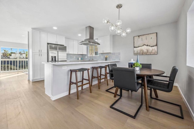 dining area featuring sink, light hardwood / wood-style flooring, and a chandelier