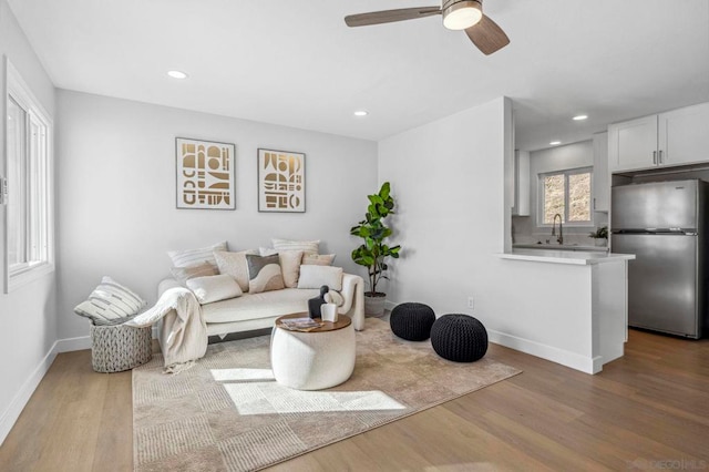 living room with sink, light hardwood / wood-style floors, and ceiling fan