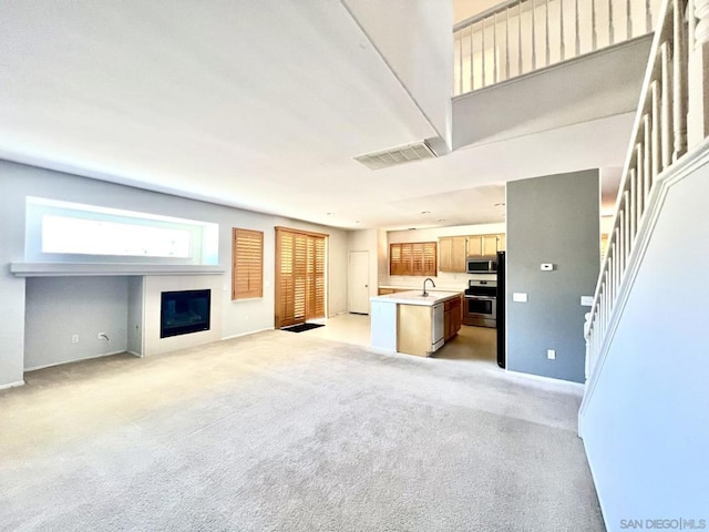 unfurnished living room with light carpet and sink