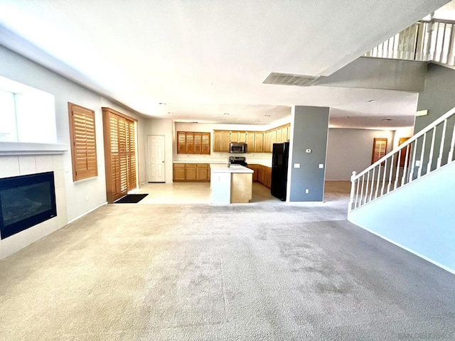 unfurnished living room featuring light carpet and a fireplace