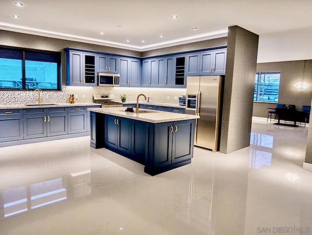 kitchen featuring appliances with stainless steel finishes, sink, a center island with sink, and backsplash