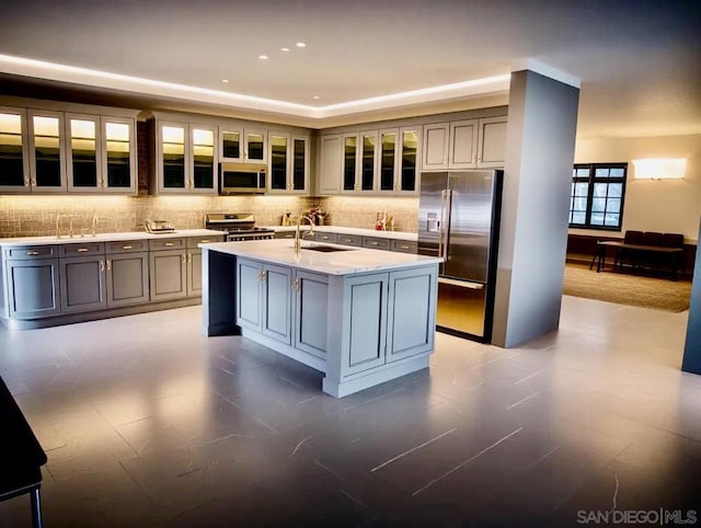 kitchen featuring an island with sink, appliances with stainless steel finishes, sink, and gray cabinetry