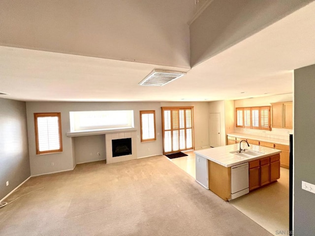 kitchen featuring dishwasher, a kitchen island with sink, light carpet, and a wealth of natural light