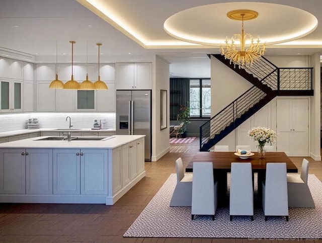 kitchen with built in refrigerator, a tray ceiling, and hanging light fixtures