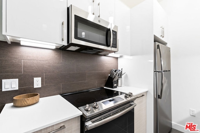 kitchen with backsplash, stainless steel appliances, and white cabinets