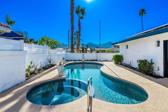 view of swimming pool with a mountain view and an in ground hot tub