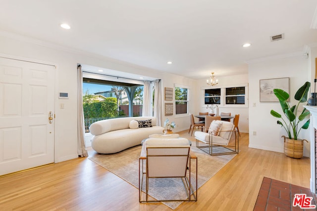 living room featuring light wood-type flooring, crown molding, and an inviting chandelier